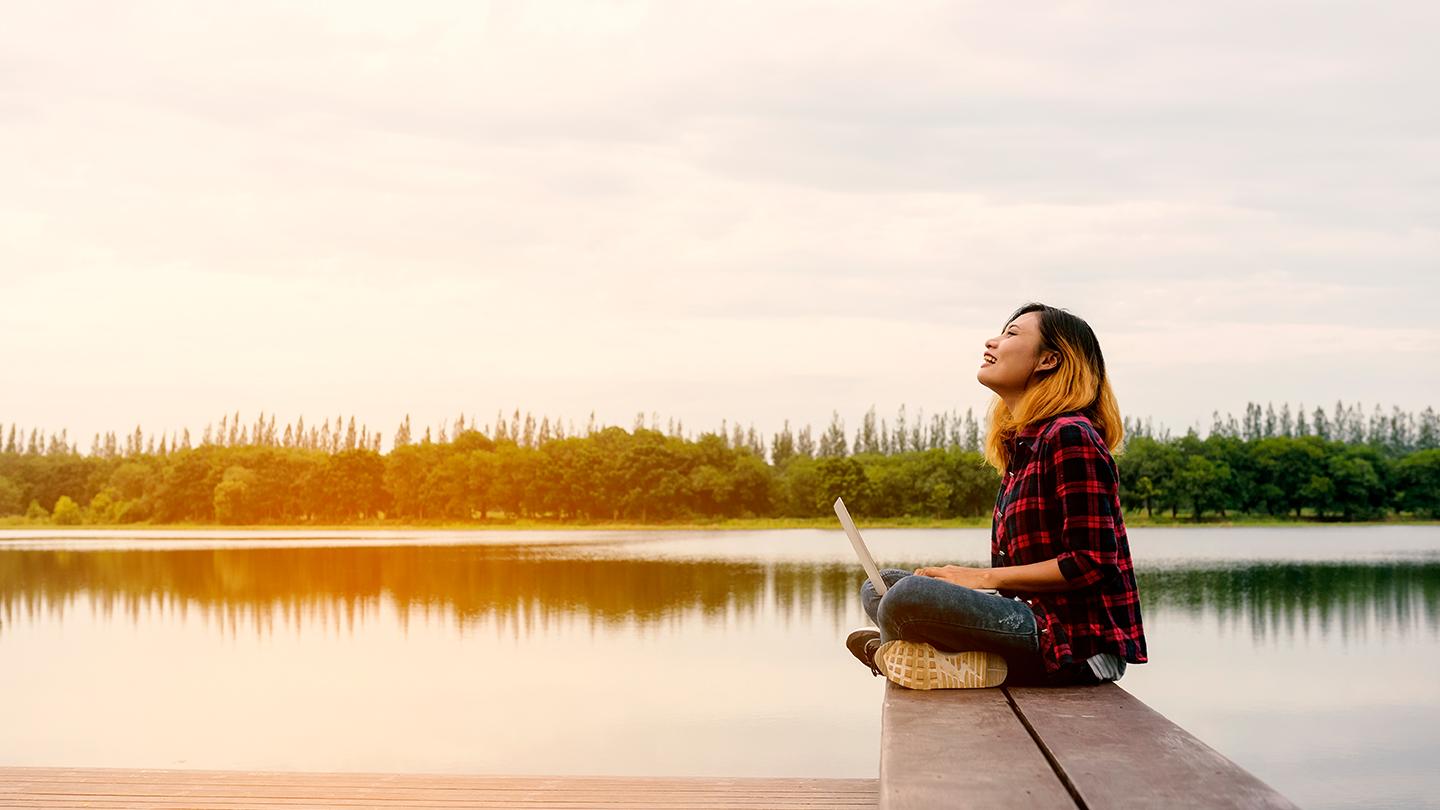 Girl sitting on lake with laptio
